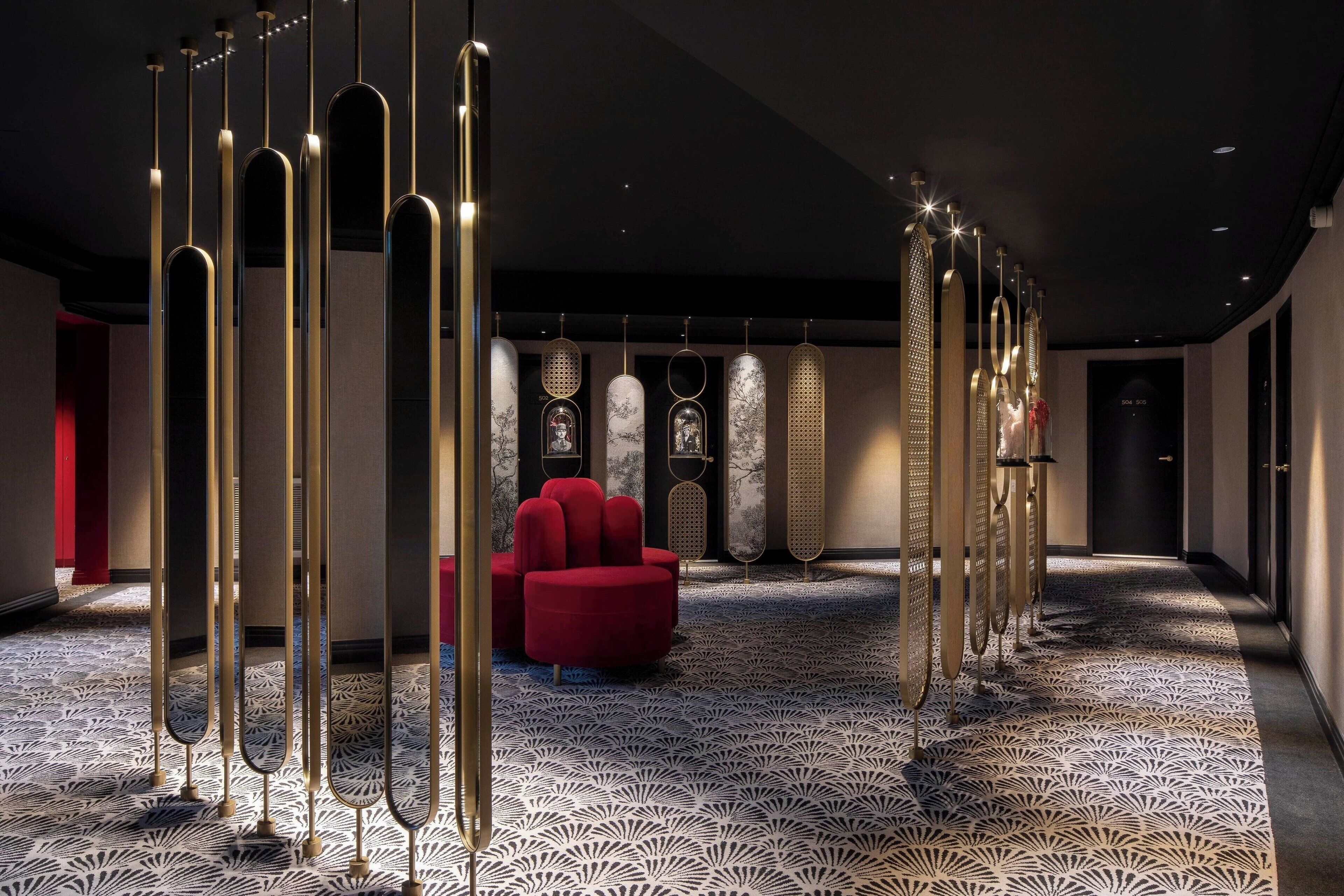 Un moderno vestíbulo de hotel con alfombra estampada, un sofá rojo y paneles decorativos en la pared.
