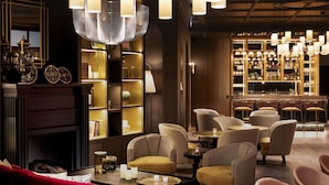 A modern bar area with multiple seating options, including sofas and chairs, and a well-stocked bar with shelves of bottles. - Maison Rouge Strasbourg Hotel&Spa, Autograph Collection (Strasbourg)