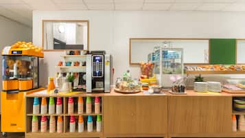 A buffet area with a coffee machine, fruit display, and stacked cups.