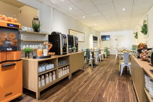Un café moderno con suelo de madera, una máquina de café y diferentes opciones de asientos, incluyendo sillas y mesas.