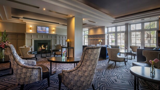 A hotel lobby with a fireplace, seating area, and large windows. - Talbot Hotel Stillorgan (Dublin)