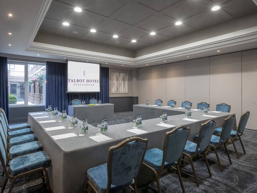 A conference room at Talbot Hotel Stillorgan with a long table, chairs, and a presentation screen.