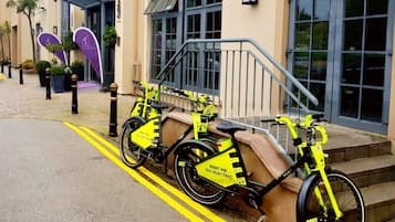 A row of yellow electric bikes parked on a sidewalk with a yellow line marking.