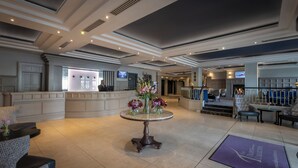 A lobby with a reception desk, a round table with floral arrangements, and seating areas. - Talbot Hotel Stillorgan (Dublin)