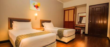 A hotel room with two beds, a desk, a chair, and a wardrobe.