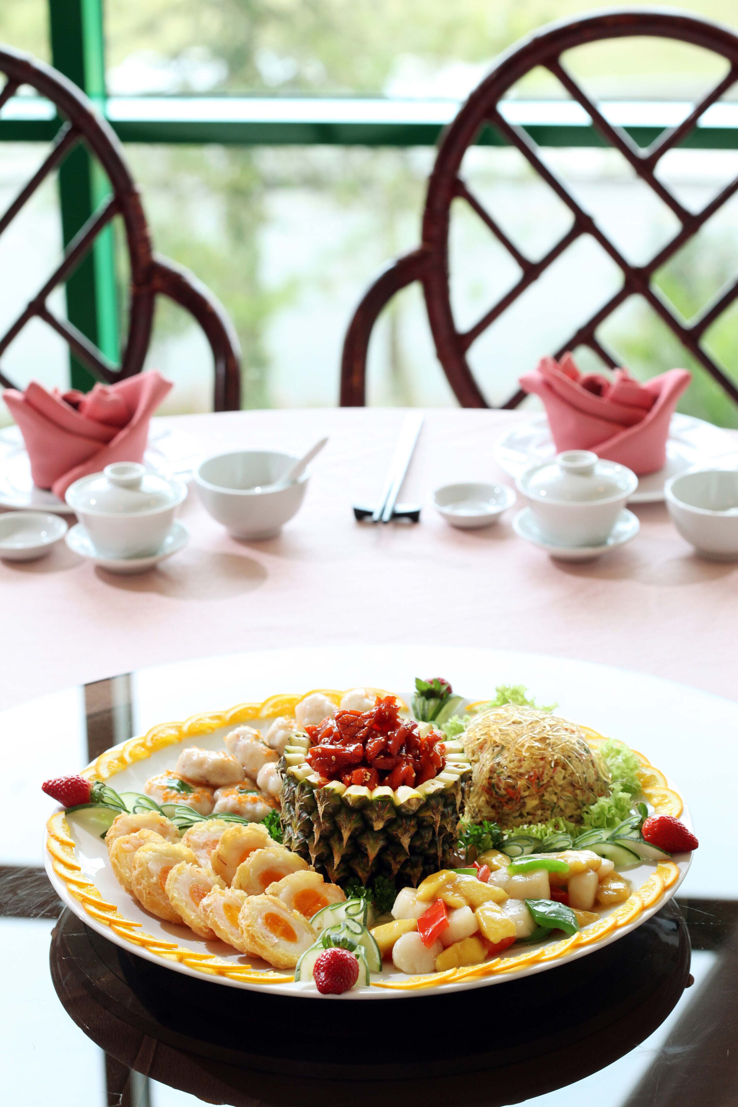 A dining table with a plate of food, bowls, chopsticks, and a pink napkin.