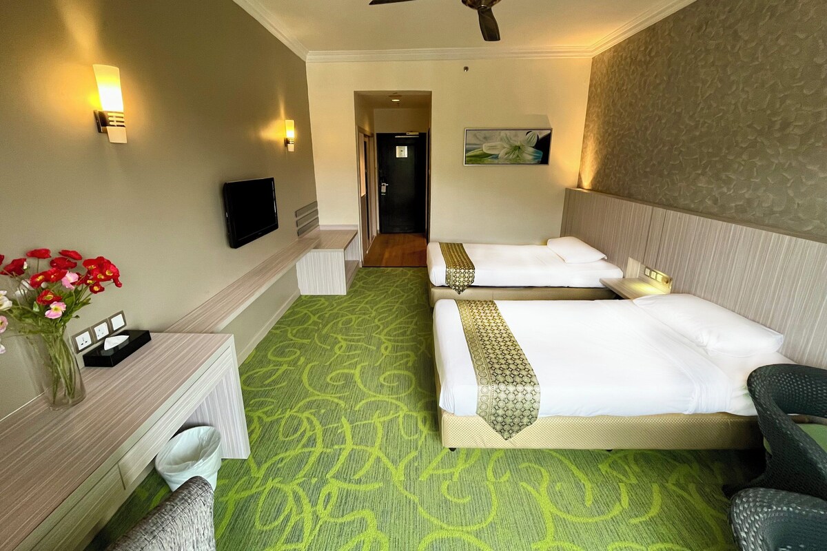 Habitación de hotel con dos camas, un escritorio, una silla, un televisor y un ventilador de techo.