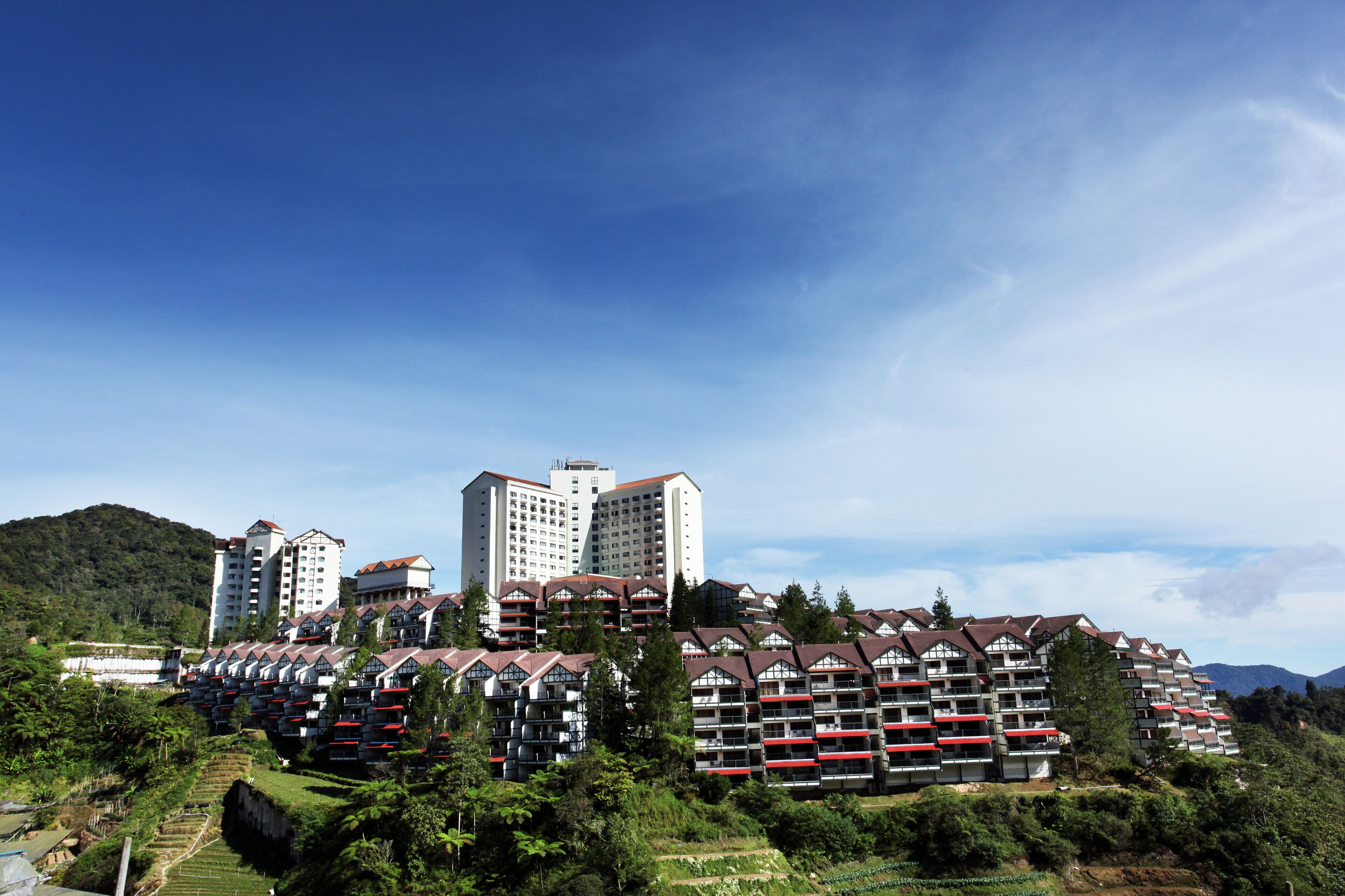 Un conjunto residencial con varios edificios de apartamentos, rodeado de vegetación y colinas.