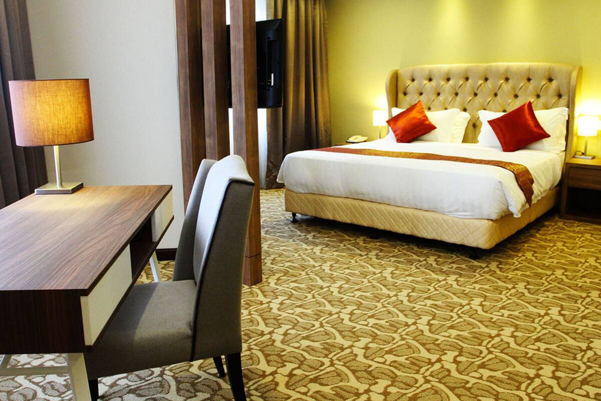 A hotel room with a bed, a desk, and a chair.