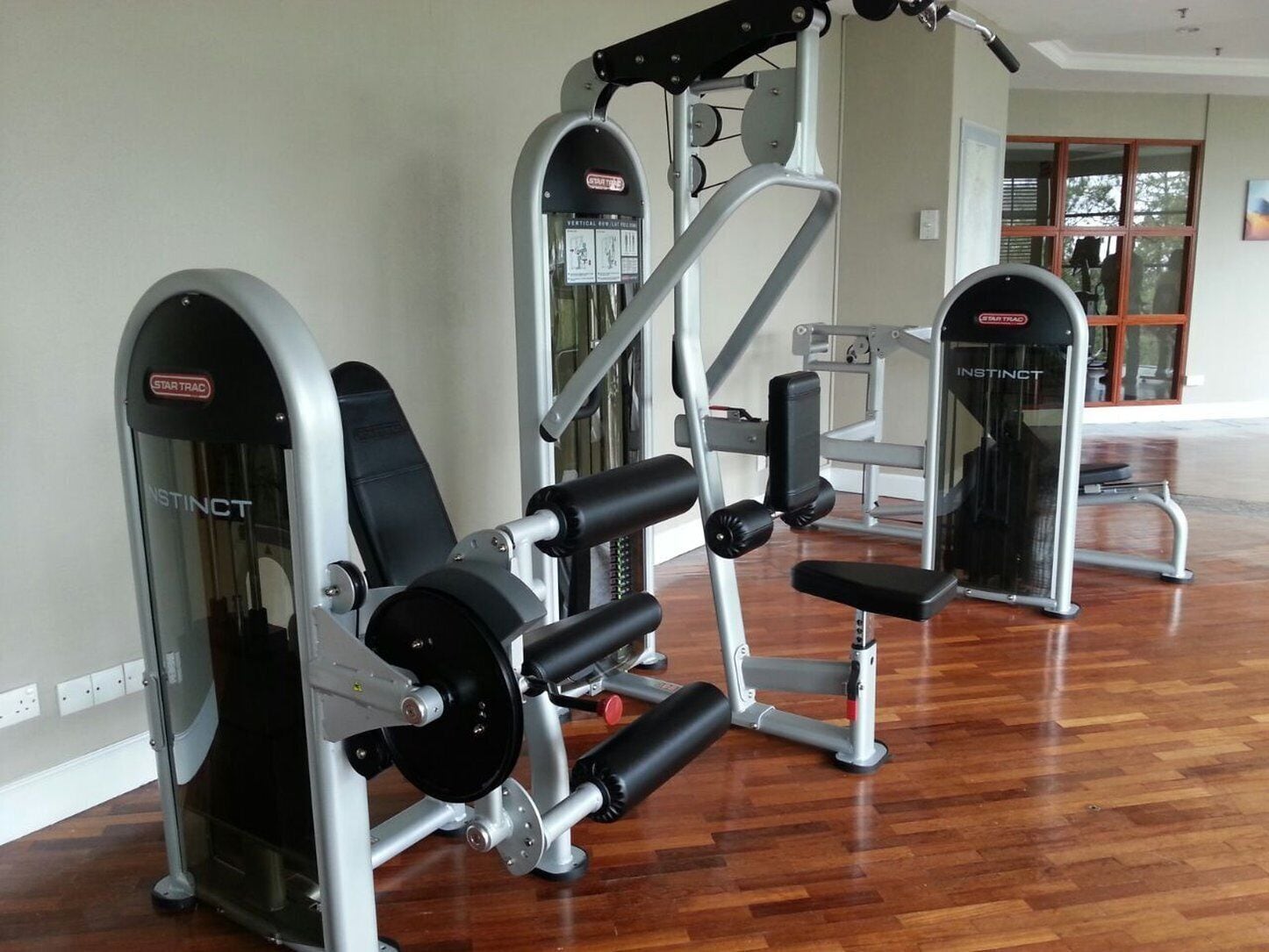 Une salle de sport équipée de machines de musculation, de bancs et d’un miroir.