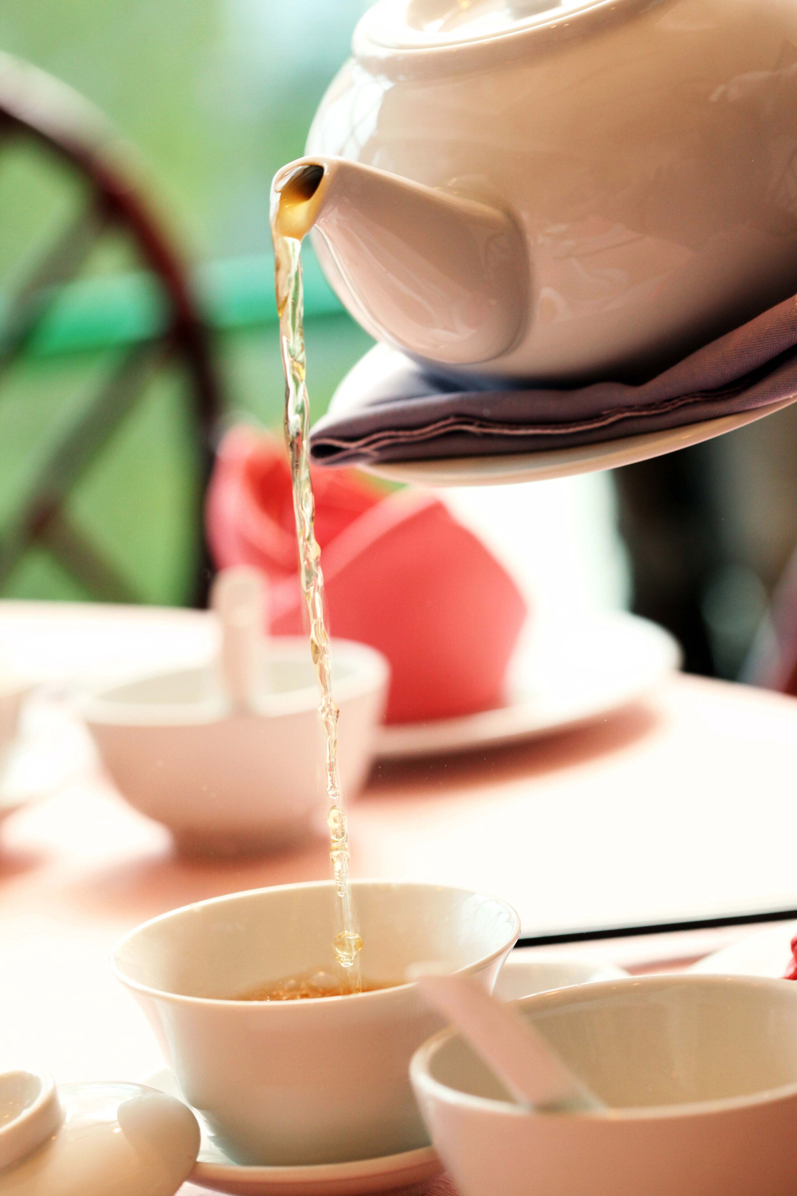 A teapot pouring tea into a cup.