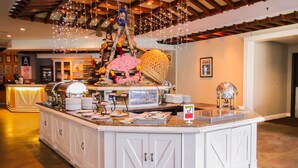 A buffet setup with a central island, overhead string lights, and a decorative umbrella. - Copthorne Hotel Cameron Highlands (Brinchang)