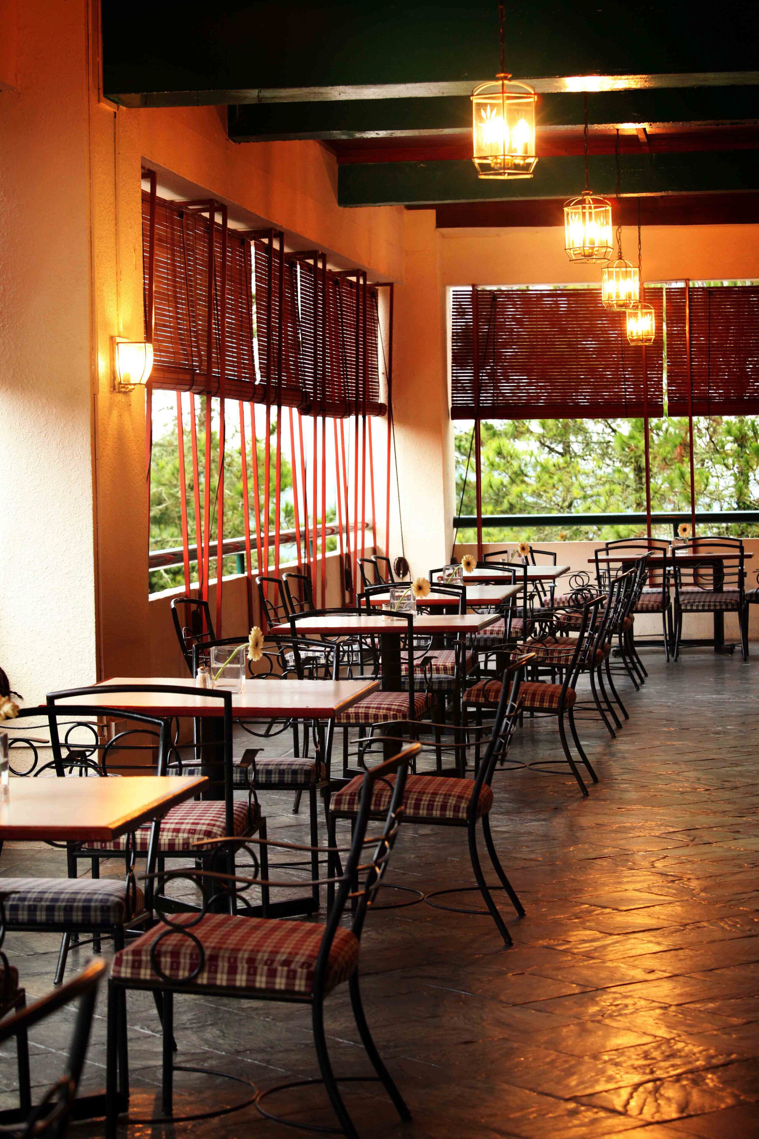 An indoor dining area with tables and chairs, wooden slats on the walls, and hanging lights.