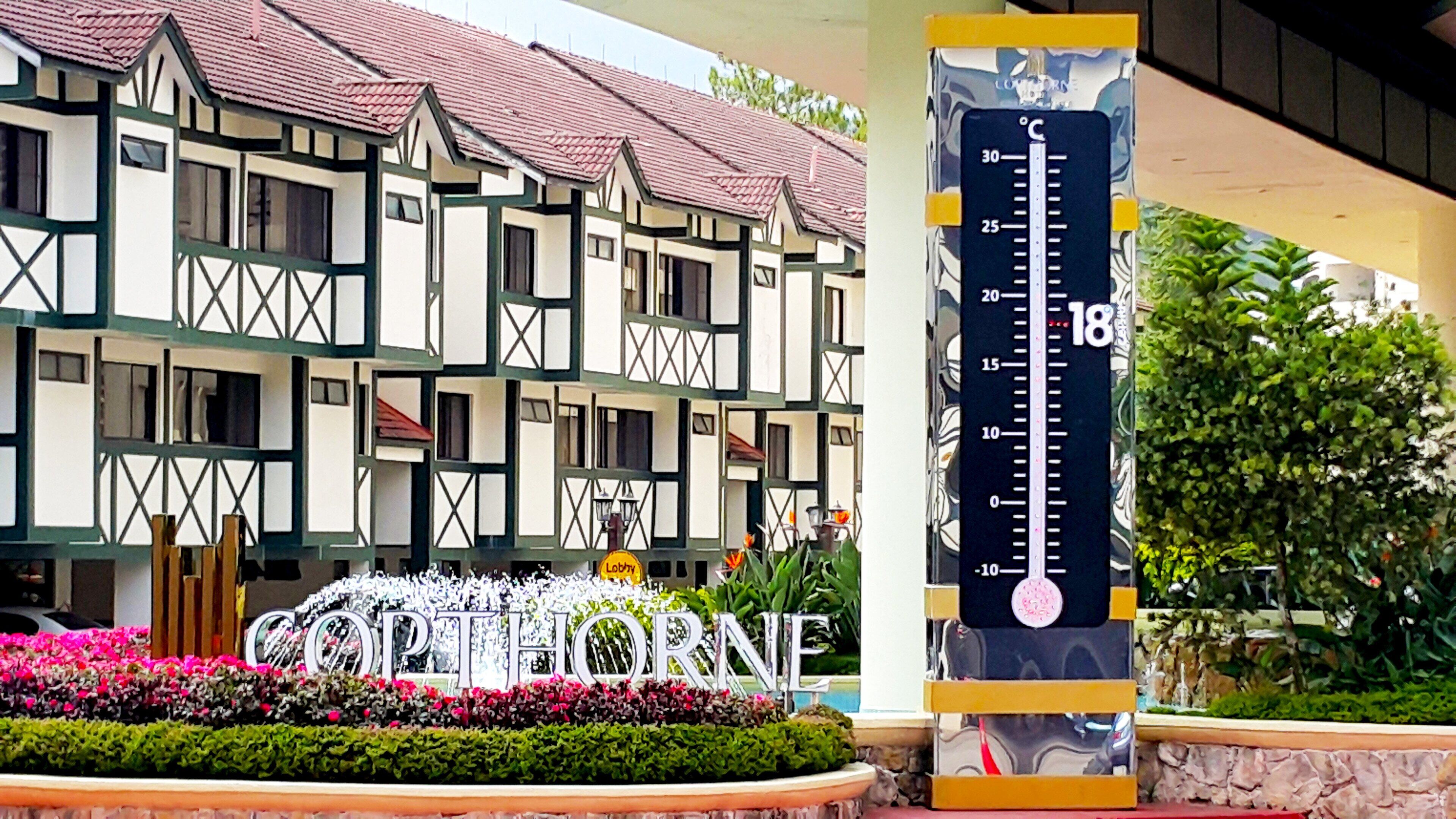 Perinteinen rakennus, jonka yläpuolella on kyltti, jossa lukee ”OPTHORNE”, ja jossa on lämpömittari, joka näyttää 18 °C.