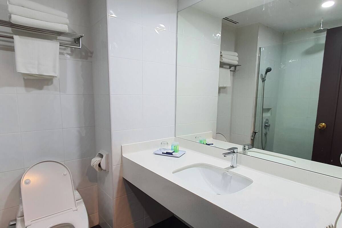 A modern bathroom with a white toilet, a sink with a mirror, and a glass shower enclosure.
