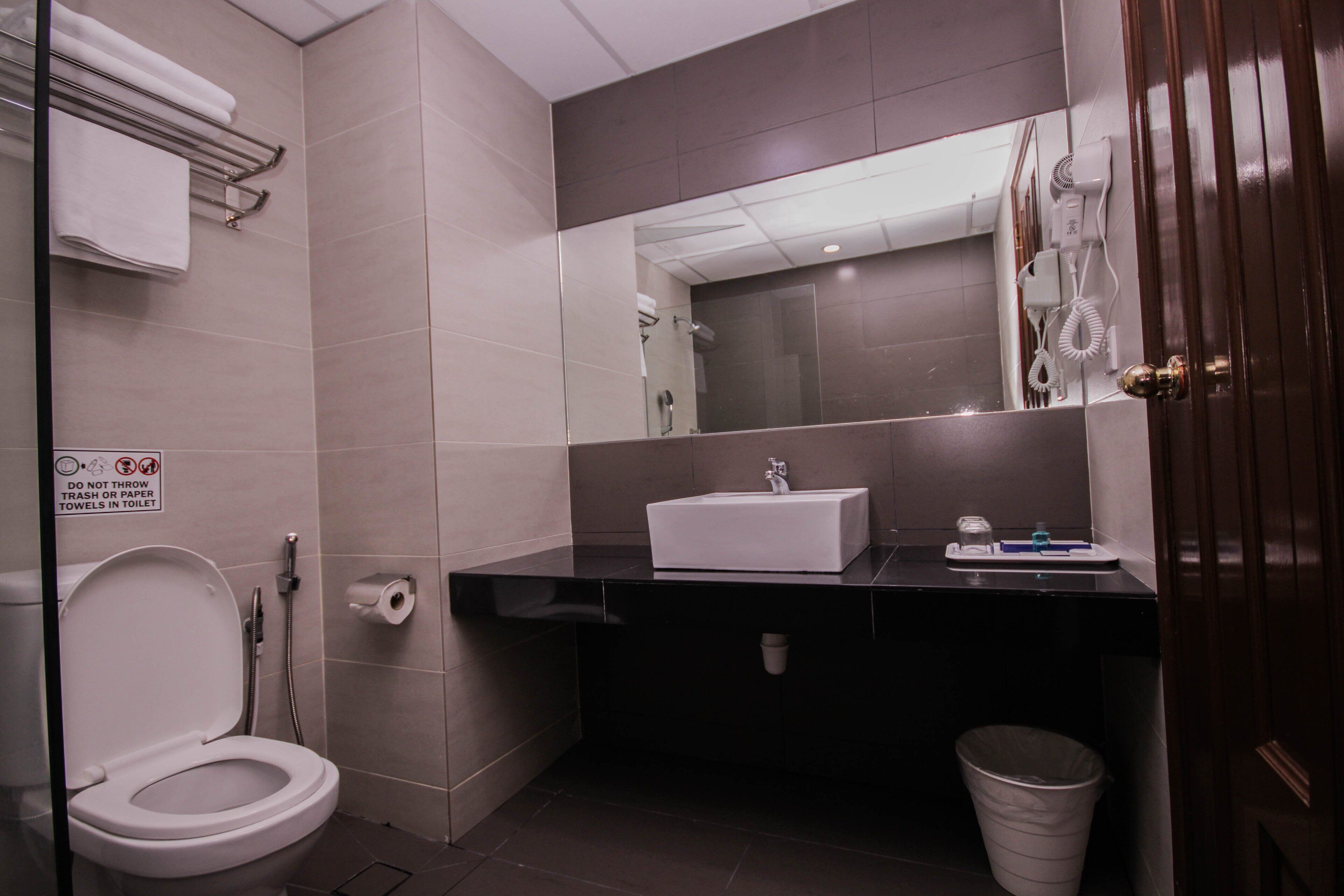 Un bagno moderno con il water bianco, un lavandino nero e uno specchio sopra.