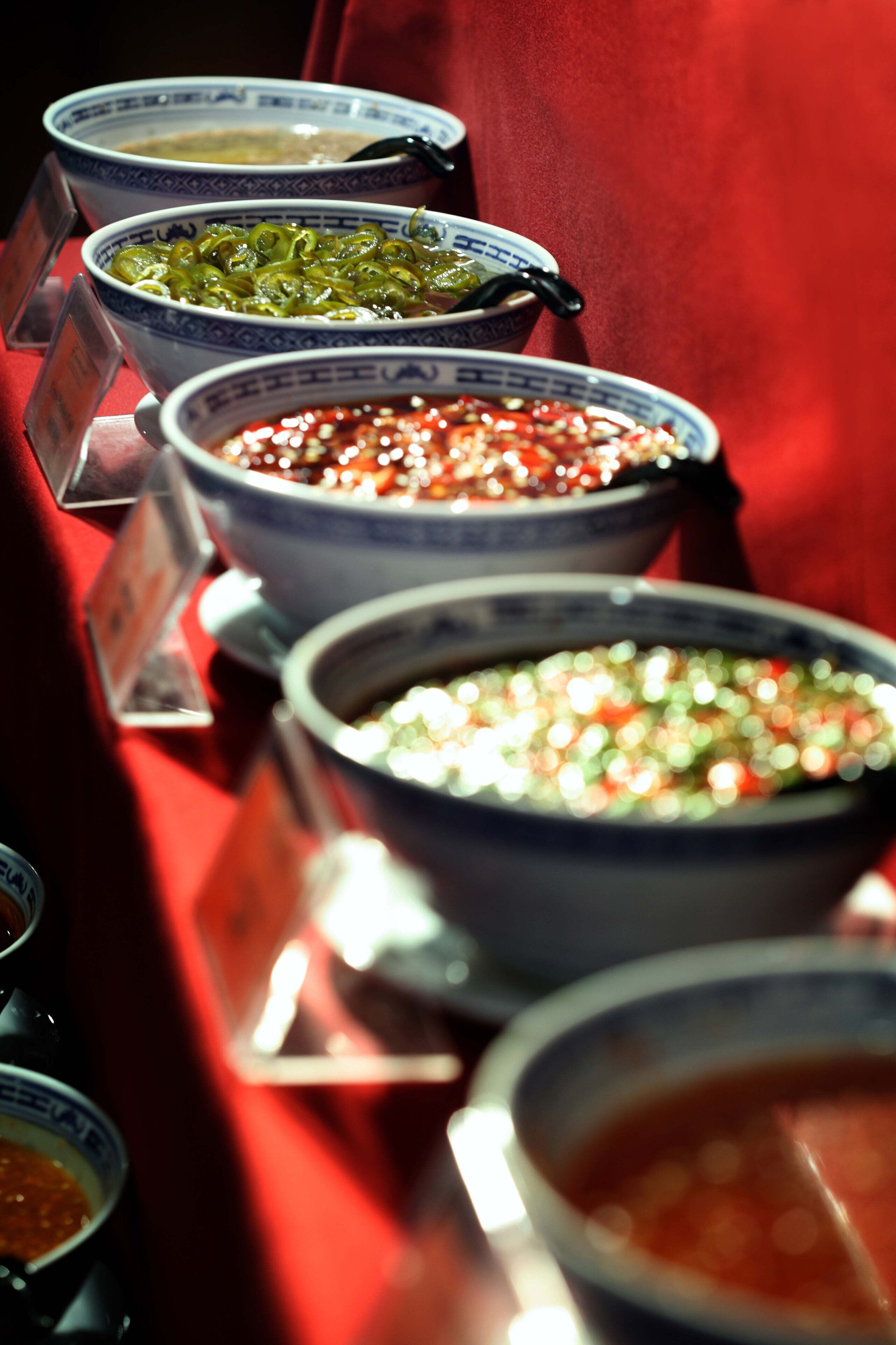 A row of bowls with different sauces on a table.