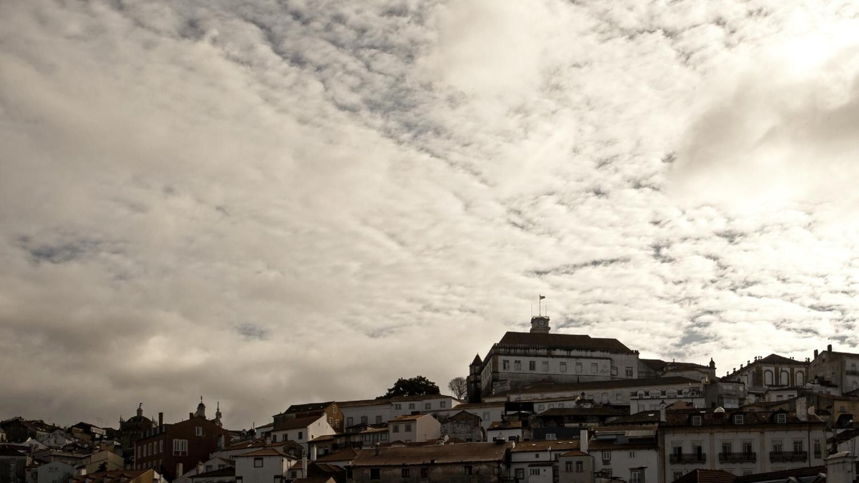 A historic town with a prominent building featuring a clock tower, surrounded by traditional architecture.