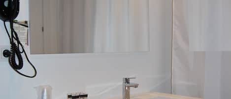 A bathroom with a white sink, mirror, and shower curtain.
