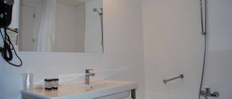 A bathroom with a sink, mirror, and shower.