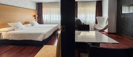Una habitación de hotel con cama, escritorio, silla y banca.