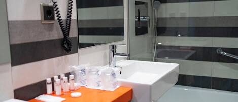 A modern bathroom with two sinks, a glass shower enclosure, and a telephone mounted on the wall.