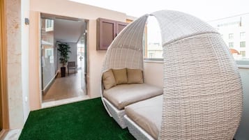 A room with a hanging chair, a small green carpet, and a view of the outside.