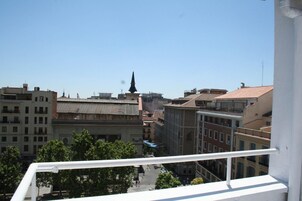 Un paisaje urbano con edificios, cielo despejado y la aguja de una iglesia a lo lejos.