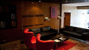 A modern living room with a black sofa, red chairs, a coffee table, and a red rug.
