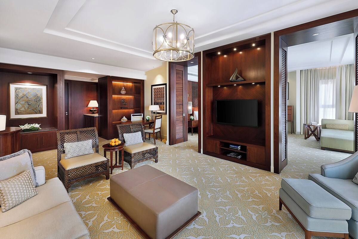 A spacious living room with a large flat-screen TV, comfortable seating, and a decorative chandelier.