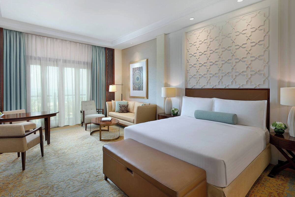 A hotel room with a large bed, a sofa, a desk, and a chair.