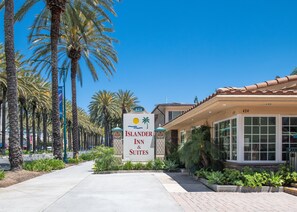 A hotel entrance with a sign for 'Islander Inn & Suites', palm trees, and a clear blue sky. - Anaheim Islander Inn and suites near Park and Convention center (Anaheim)