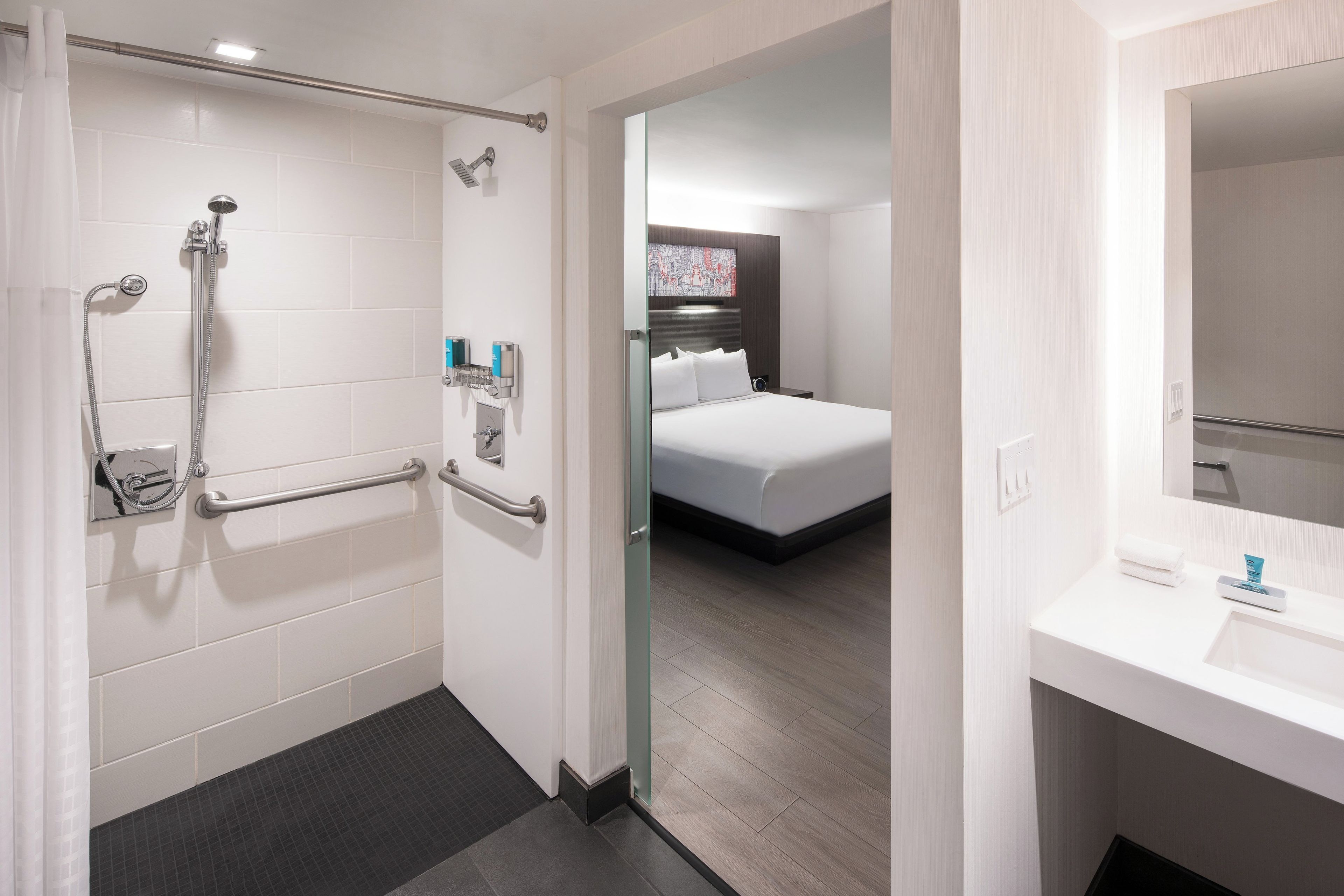 A hotel bathroom with a shower, grab bars, and a toilet.