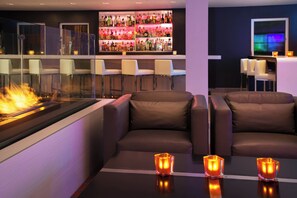 Un espace bar avec un assortiment de bouteilles d’alcool, un foyer et des sièges agrémentés de bougies.