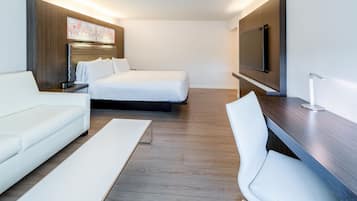 Una habitación de hotel moderna con cama, sofá, escritorio y televisión.