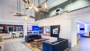 Eine moderne Hotelhalle mit Sitzgelegenheiten und einer Bar, sowie ein großes 'a'-Logo an der Wand.