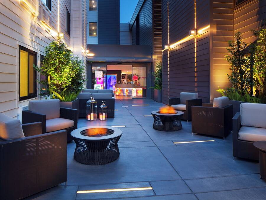 Un’area relax all'aperto con brasiere e poltrone lounge, circondata da muri con illuminazione integrata.