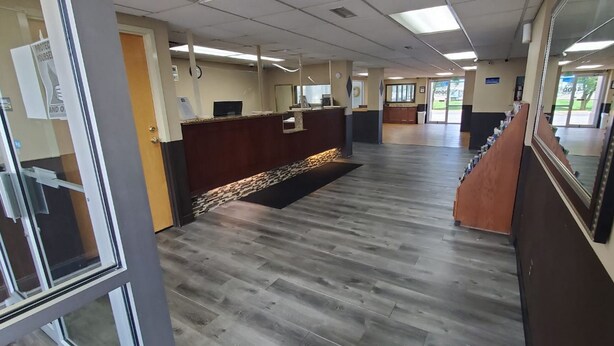 A reception area with a wooden floor, a reception desk, and a large mirror on the right. - FairBridge Inn Express Indianapolis South (Indianapolis)