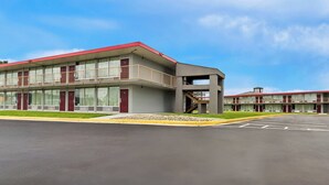 Un motel con una estructura de dos pisos, una galería techada y un estacionamiento.