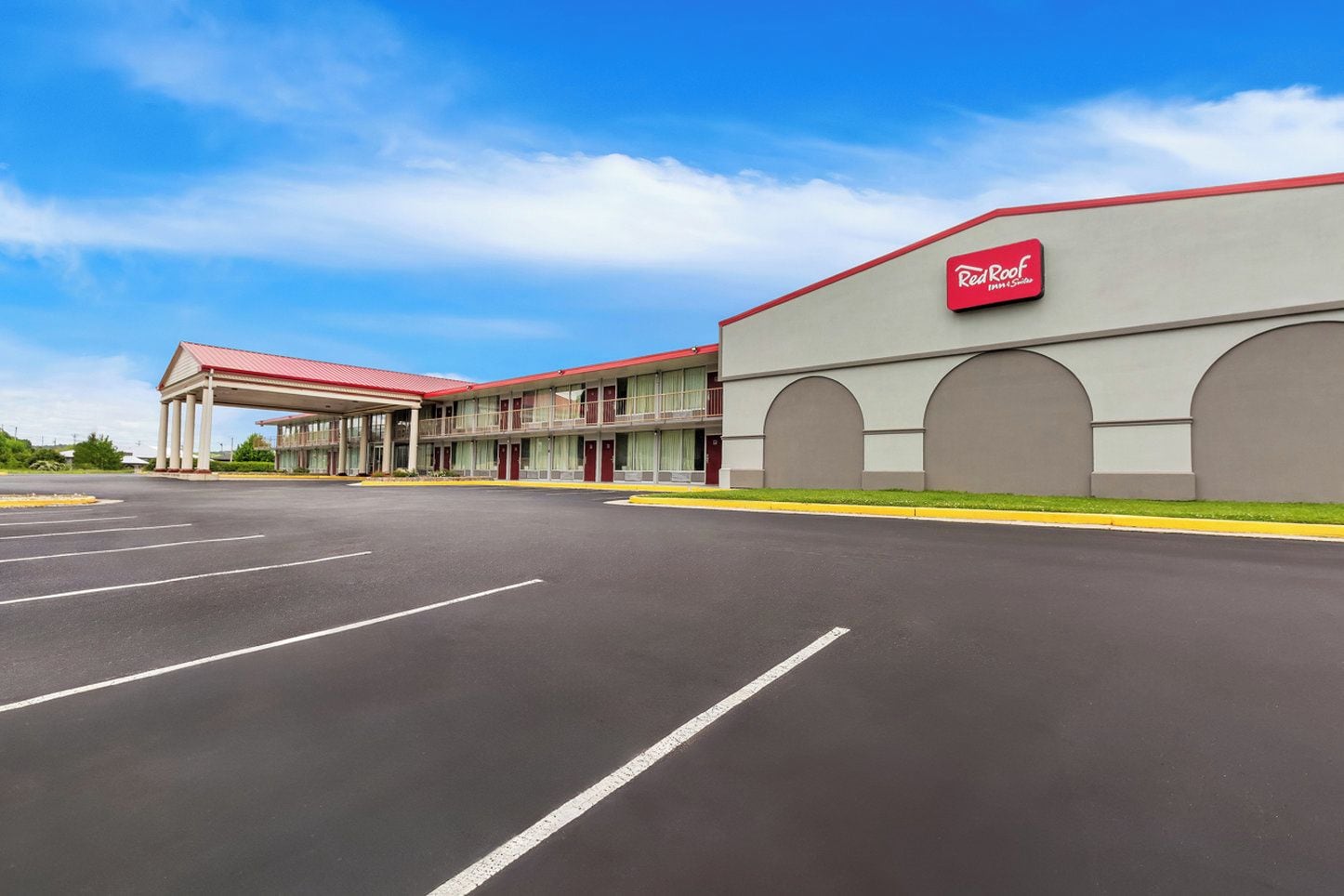 A Red Roof Inn with a large parking lot and a two-story building with a red roof and beige walls.