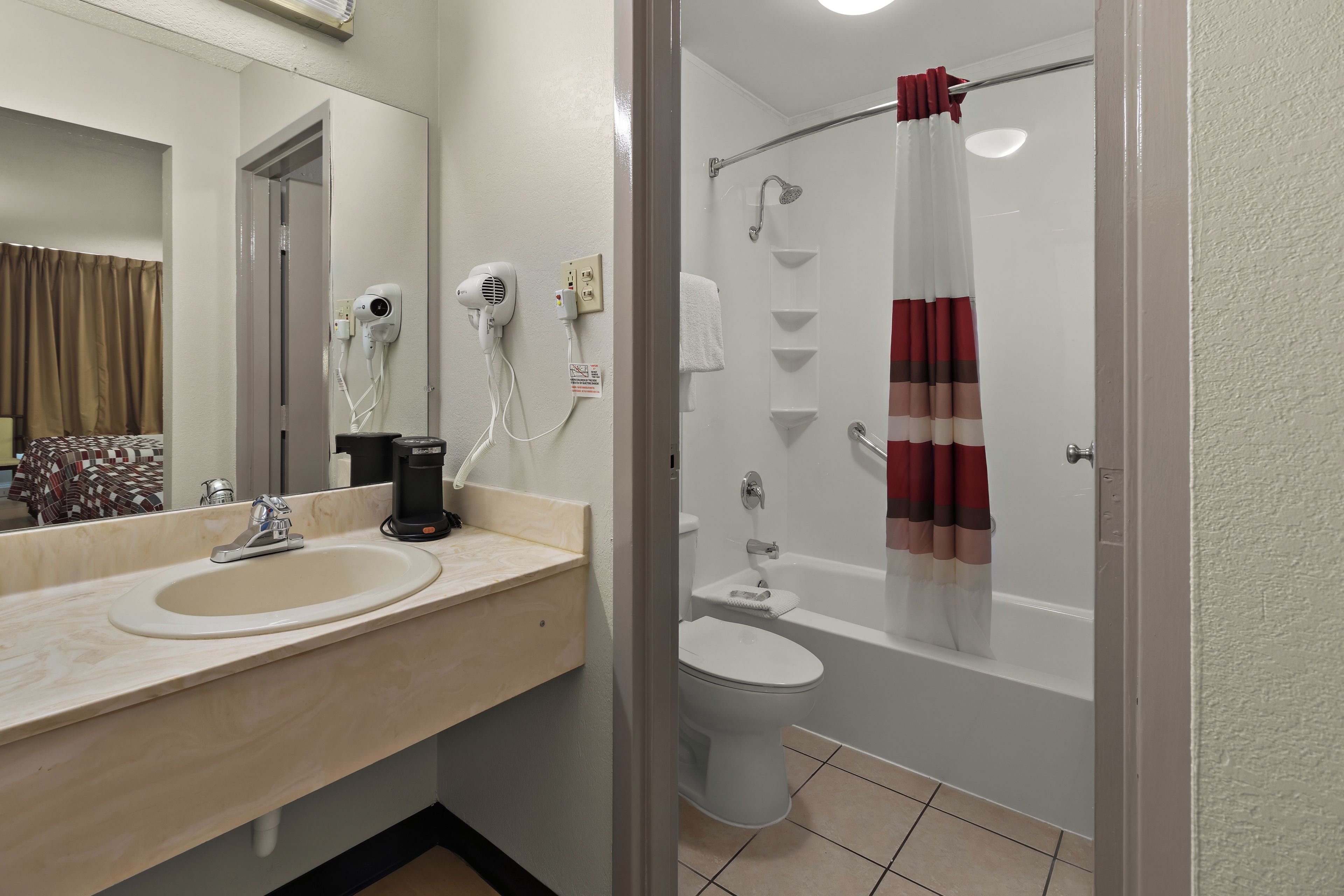 Un baño con lavabo, espejo, secador de pelo y ducha.