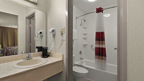 Een badkamer met een wastafel, spiegel, haardroger en douche.