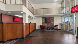 Een hotel lobby met een receptiebalie, een accentmuur van steen en een trap.