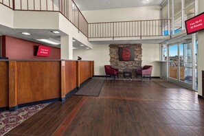Un vestíbulo de hotel con una recepción, una pared de acento de piedra y una escalera.