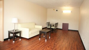 Une pièce avec un canapé blanc, une petite table, une table à manger avec des chaises et une lampe.