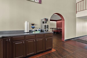 Una cocina con cafetera, microondas y refrigerador. Hay un mostrador con pileta y alacenas.