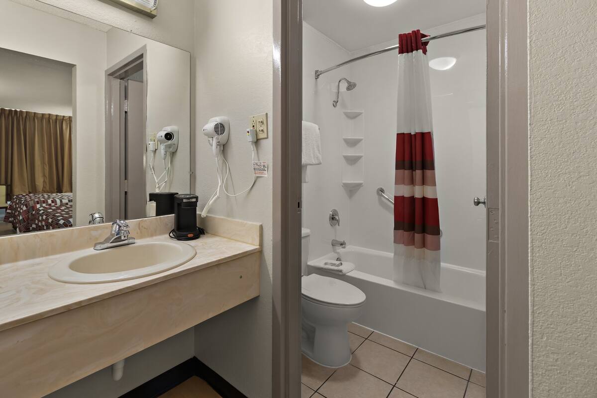 Een badkamer met een wastafel, spiegel, haardroger en douchegordijn.