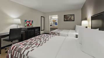A hotel room with two beds, a desk with a computer, a TV, and a bathroom visible through an open door.