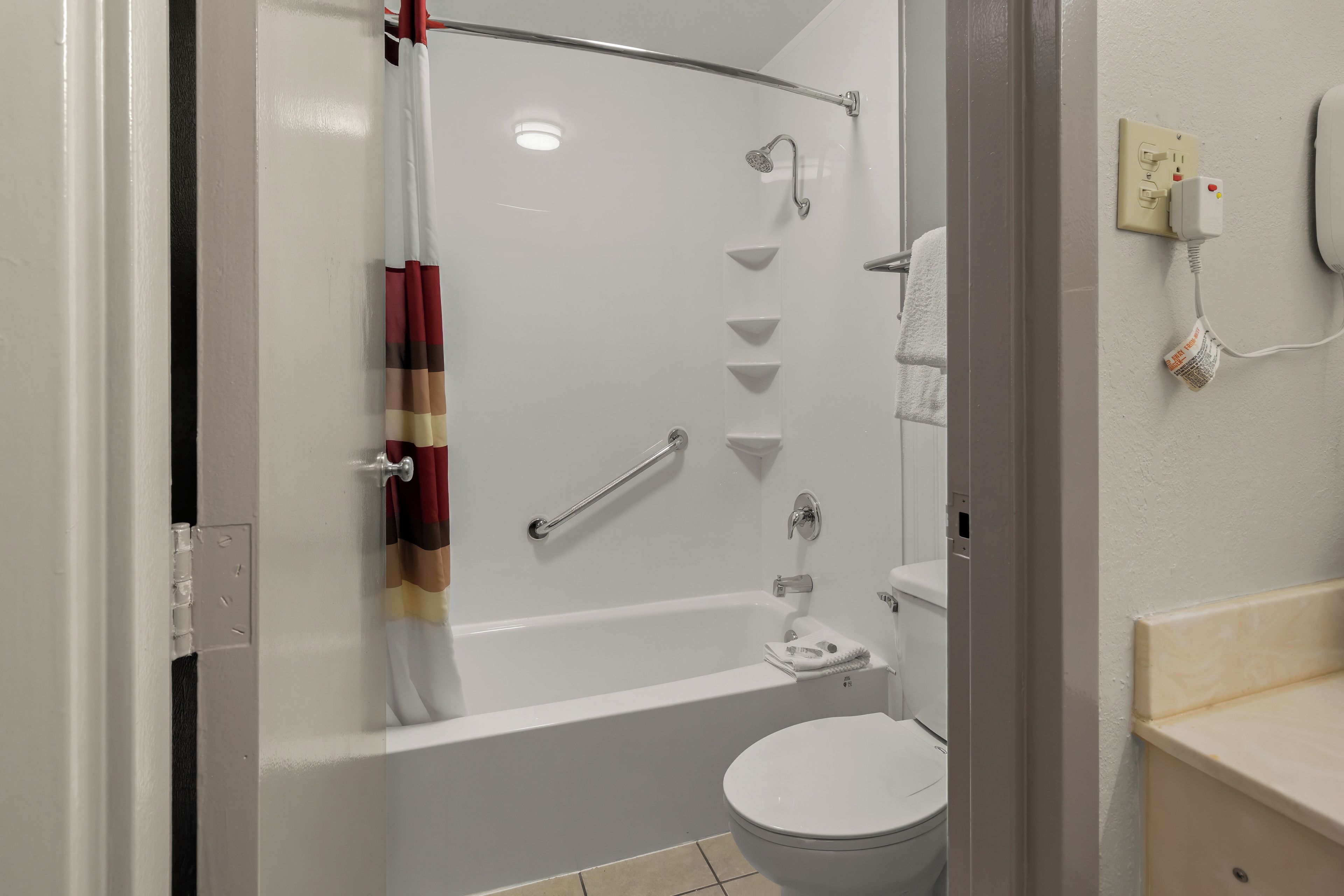 A bathroom with a shower, toilet, and a towel rack.