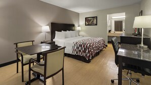 Une chambre d’hôtel avec un lit, un bureau, une chaise et une petite table.